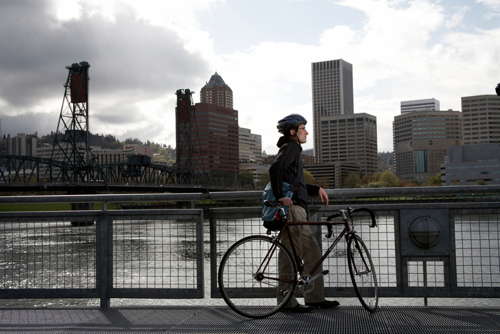 USA, Oregon, Portland, man with bicycle looking at skyline over river