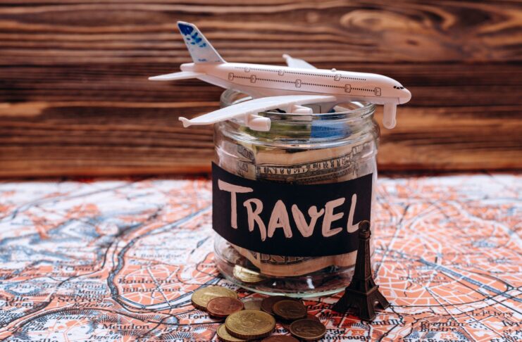 Collecting money for travel, money savings in a glass jar with world map