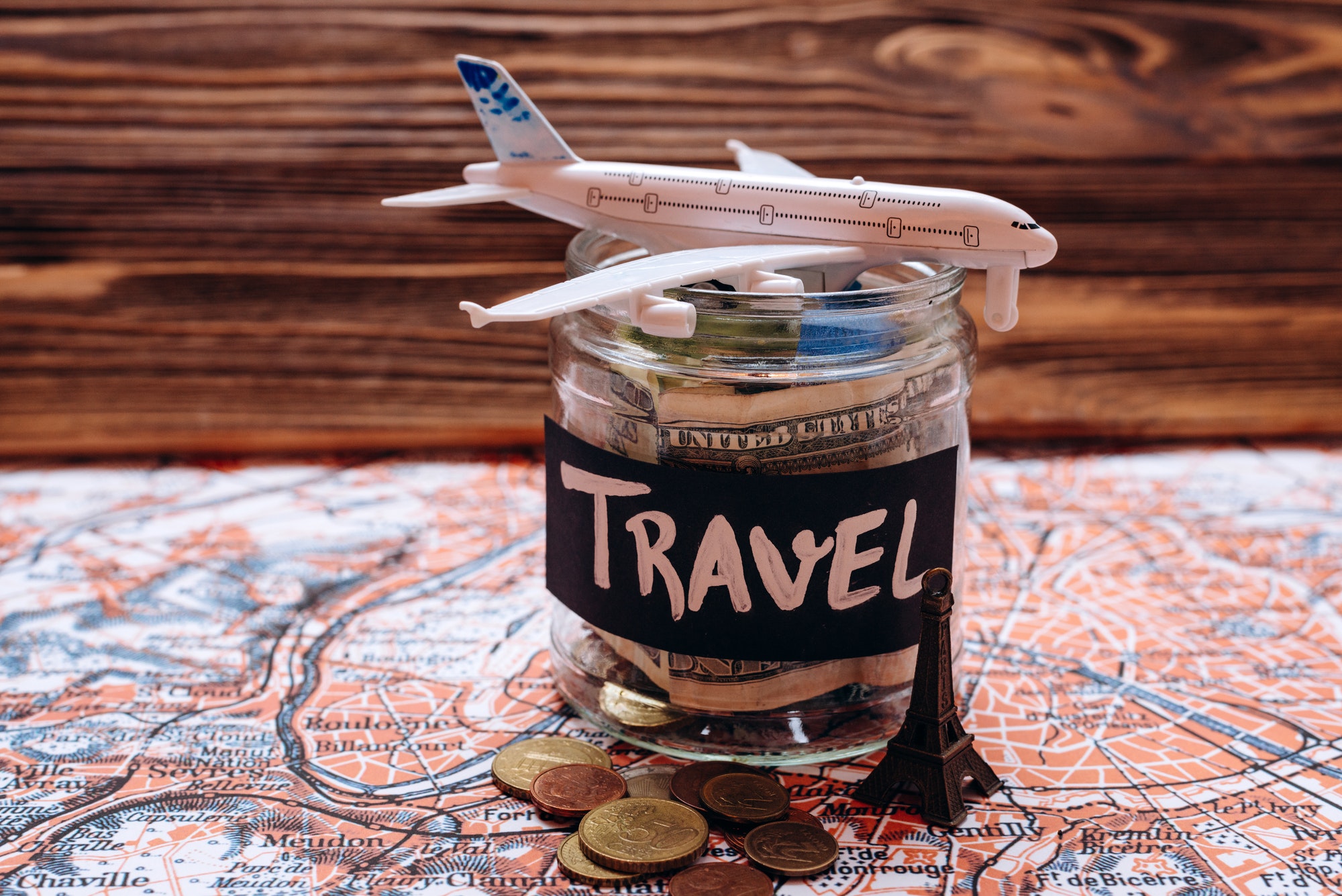 Collecting money for travel, money savings in a glass jar with world map