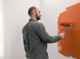 Man renovating apartment with orange paint