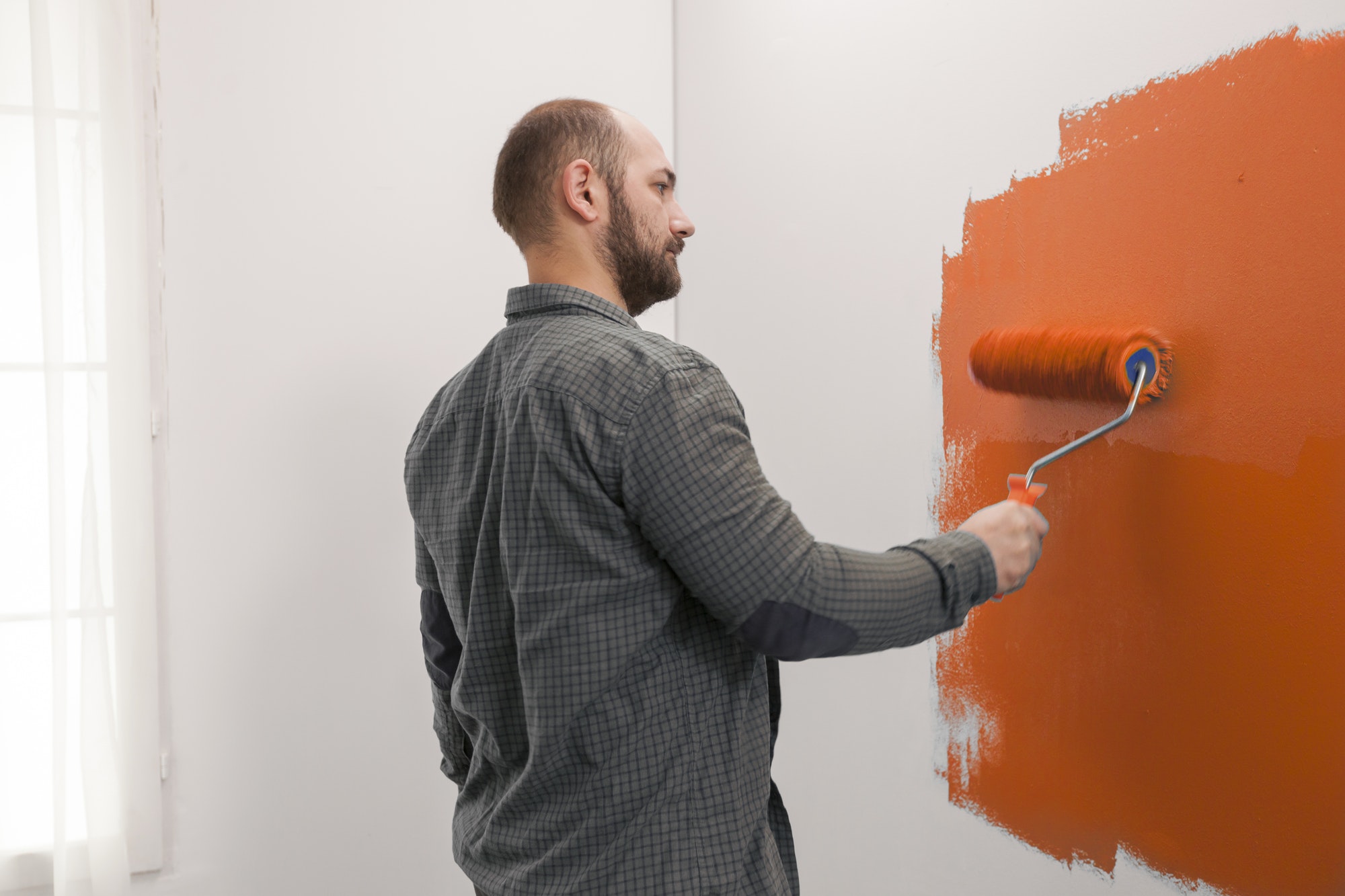 Man renovating apartment with orange paint